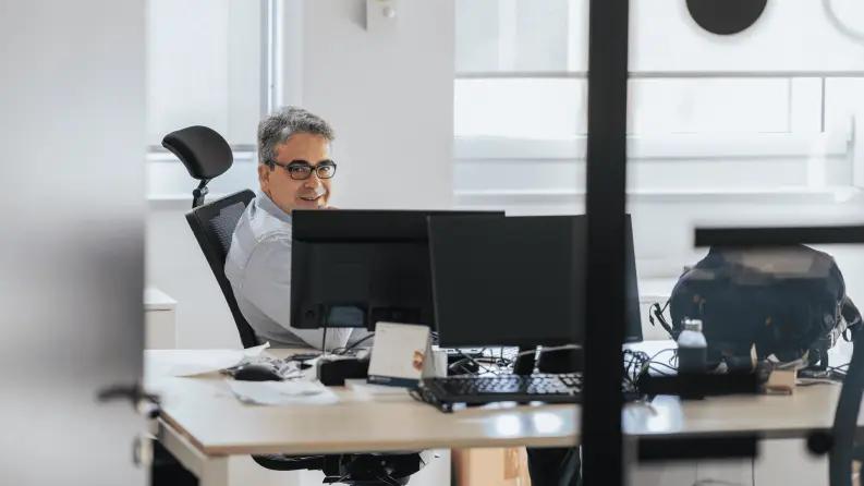 Professional working at a modern office desk with multiple screens