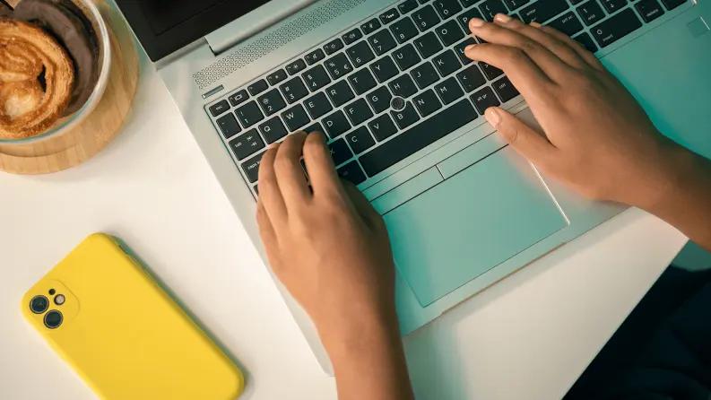 Hands typing on a laptop keyboard, working on a computer