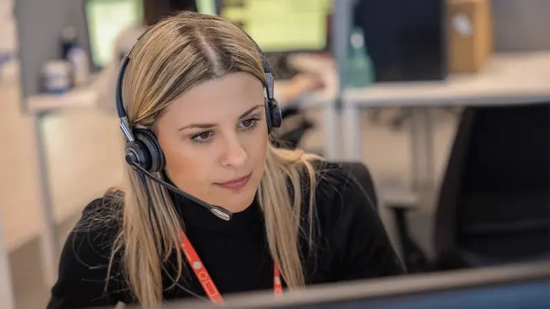 Woman with a headset working at a computer in a call center.