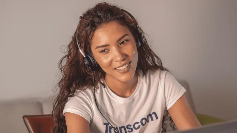 Smiling female agent wearing a headset during a virtual call.